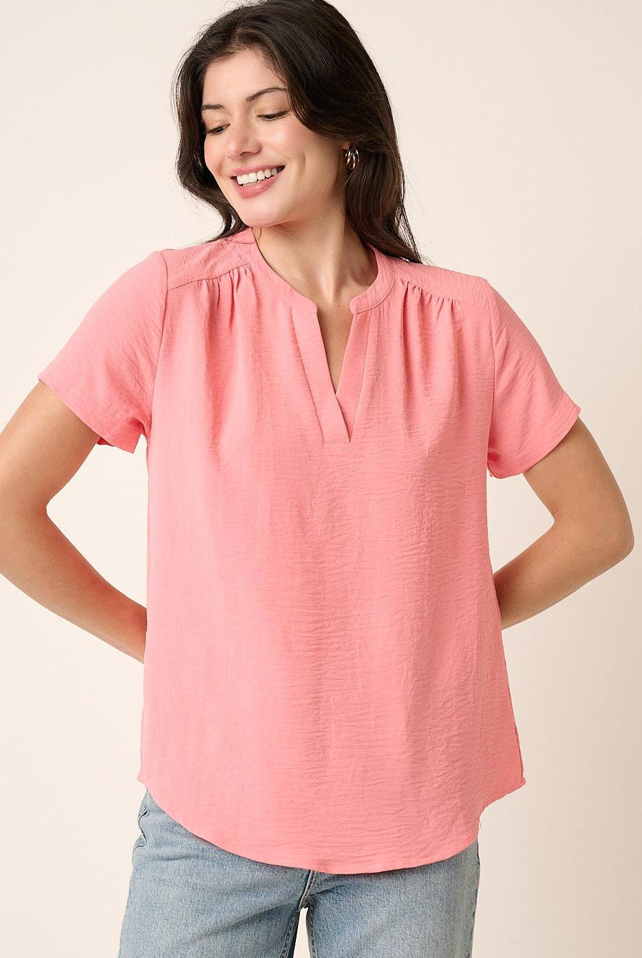 Woman wearing a pink blouse with short sleeves on a beige background