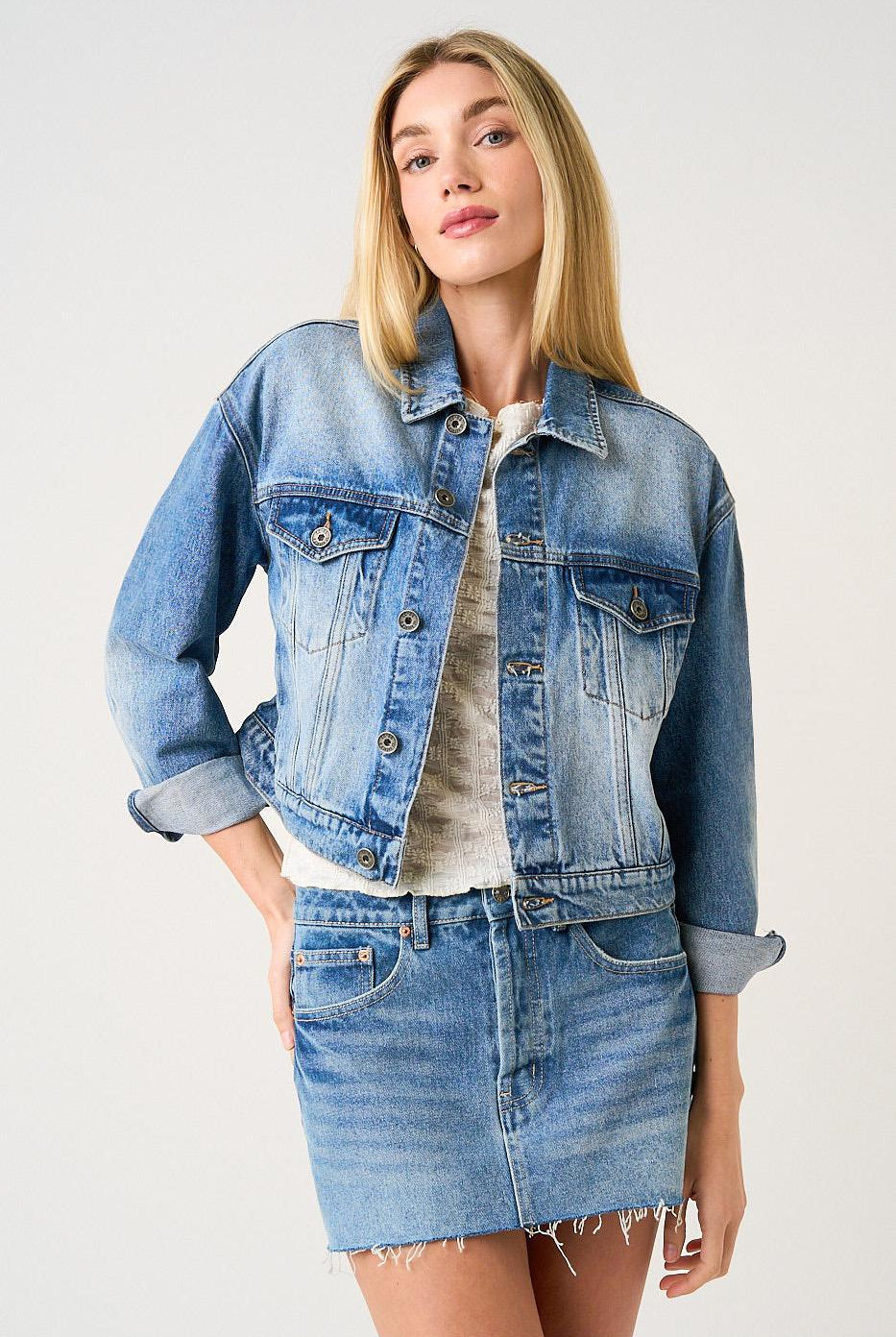 Woman wearing a denim jacket and skirt on a white background