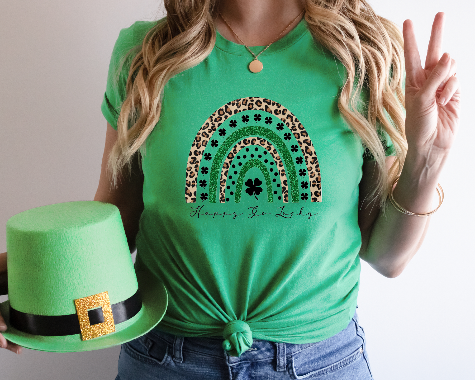 Person wearing a green t-shirt with a rainbow design and holding a green hat.