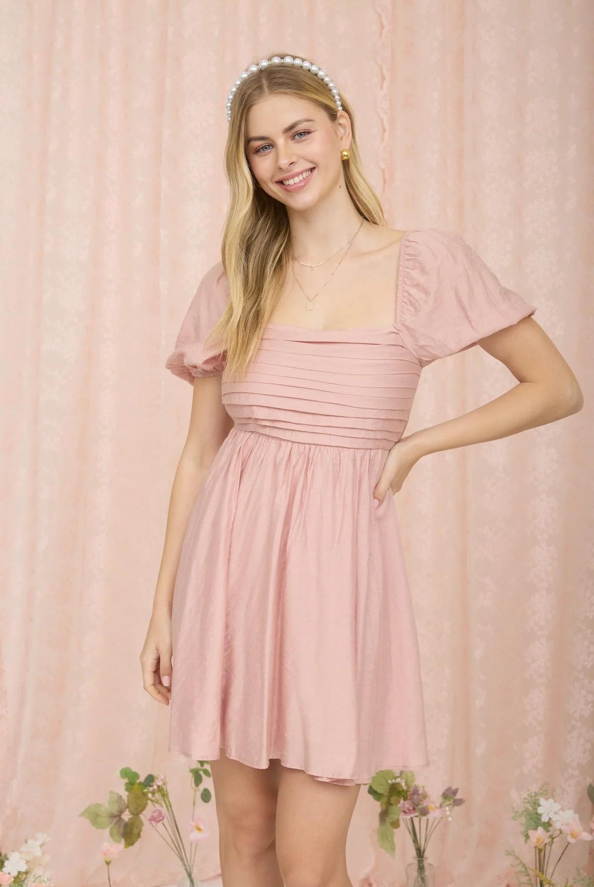 Woman wearing a pink dress against a matching pink background