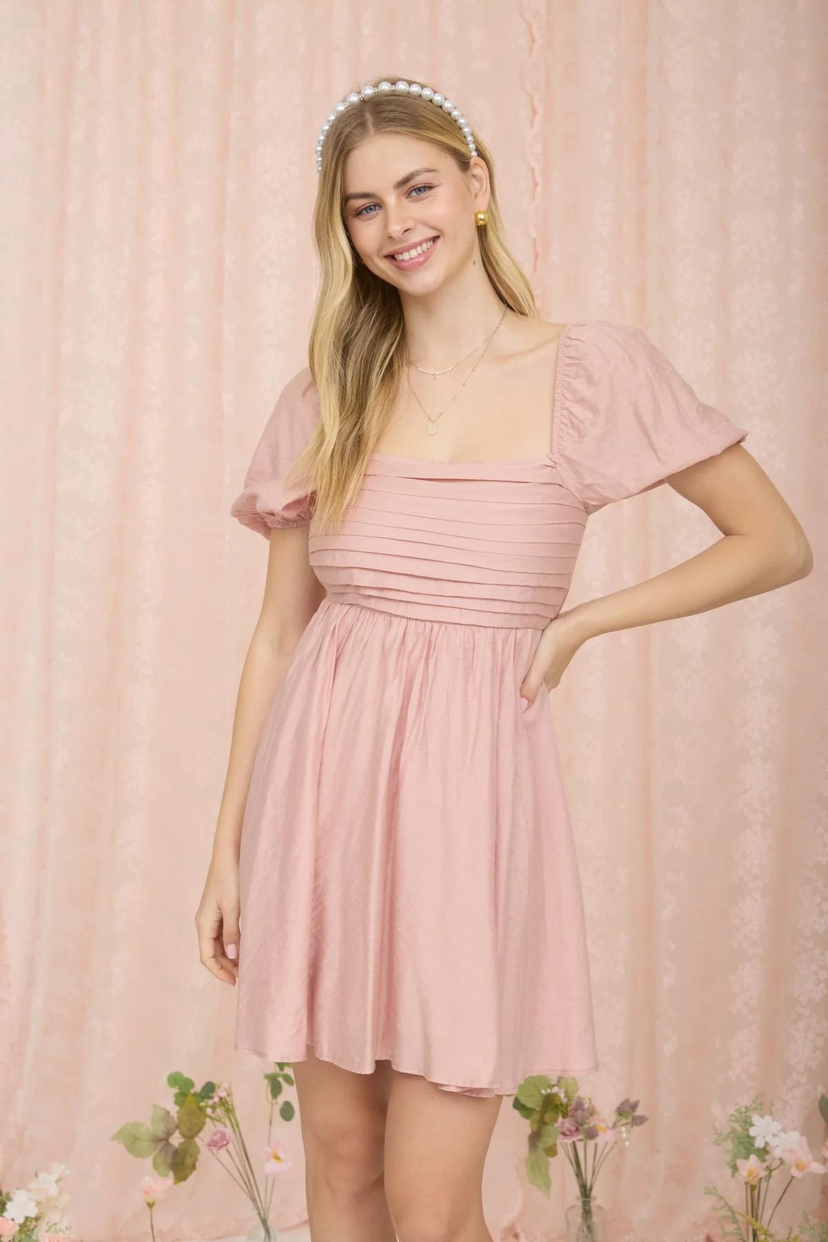 Woman wearing a pink dress against a matching pink background
