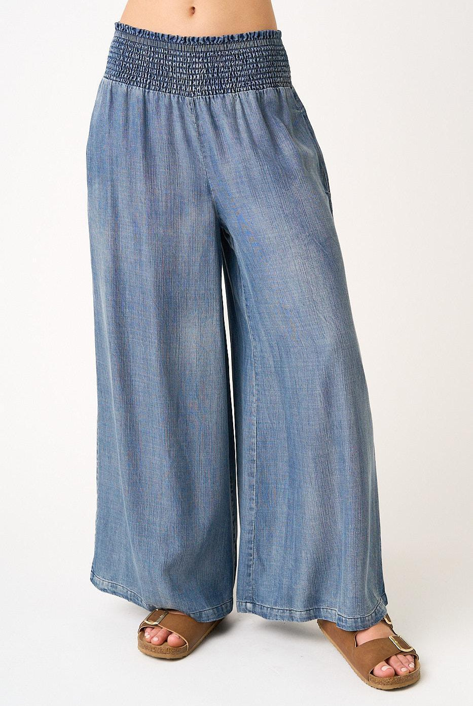 Blue denim wide-leg pants worn by a person on a white background