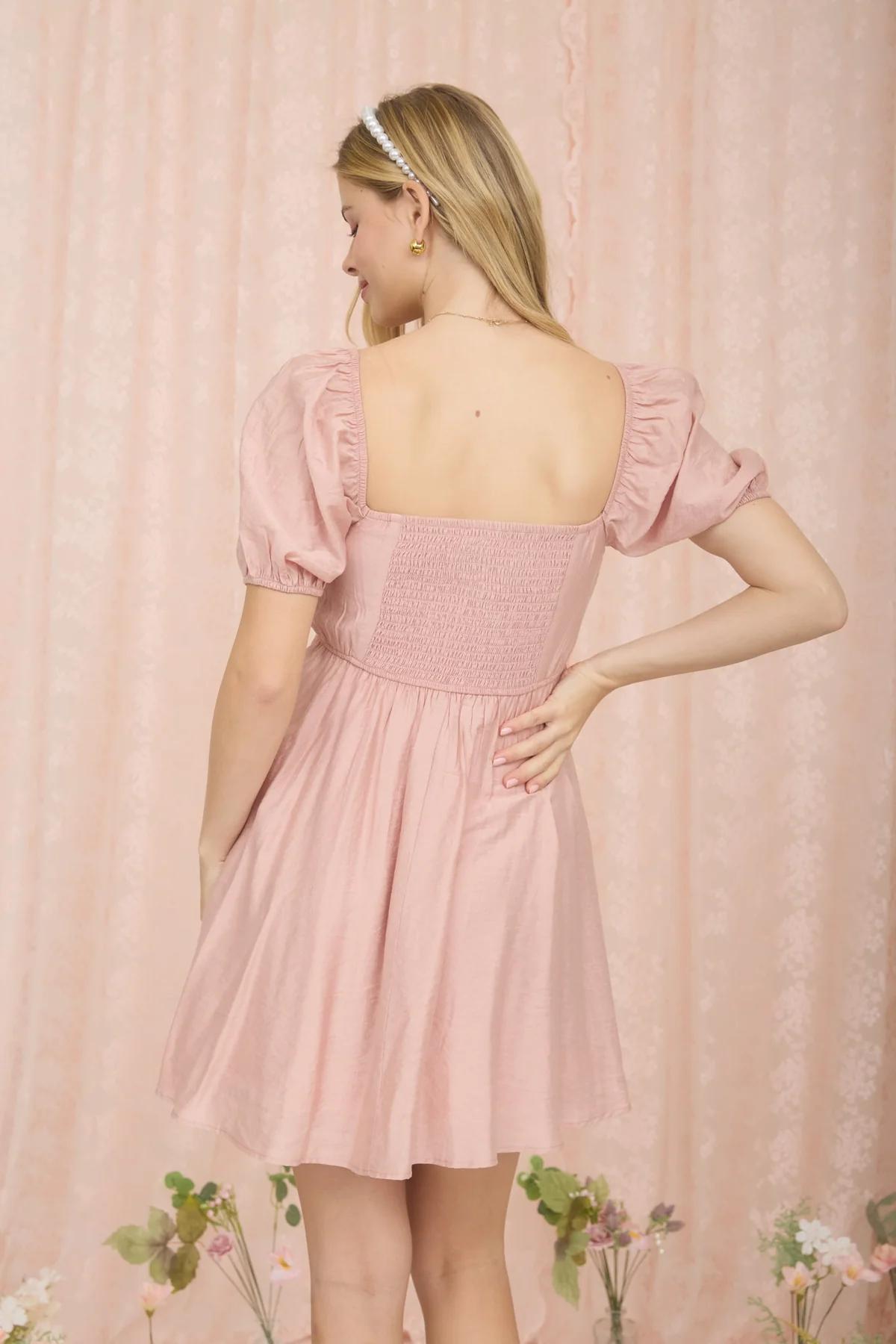 Woman wearing a pink dress against a matching pink curtain backdrop