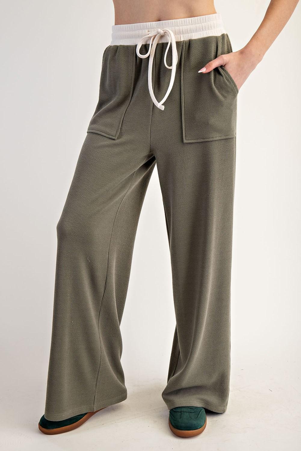 Woman wearing a green outfit with a green and white top on a plain background