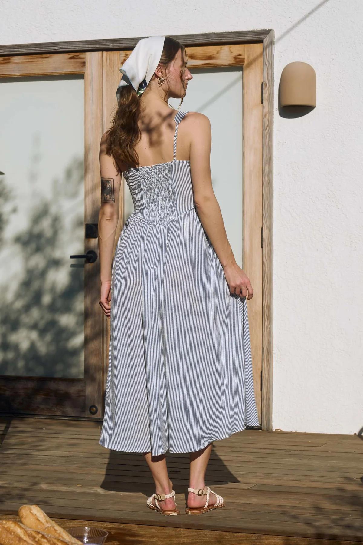 Woman in a light blue dress standing on a wooden deck.