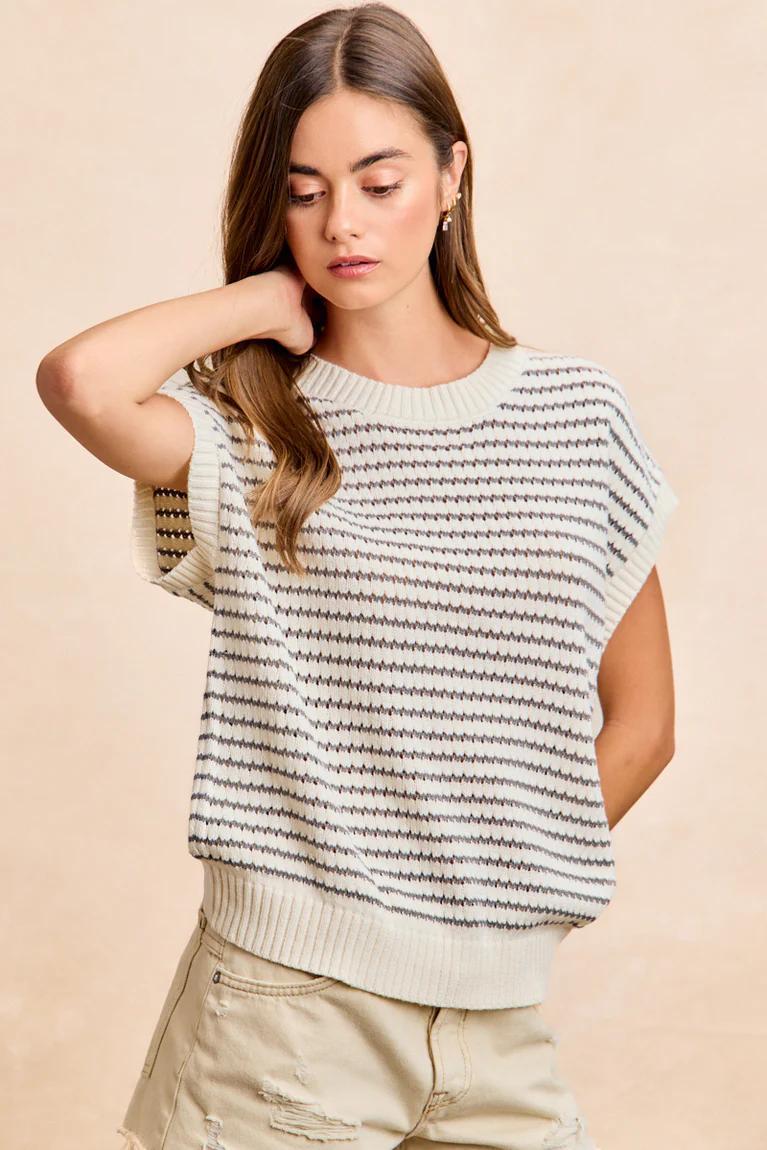 Woman wearing a striped sleeveless sweater against a beige background