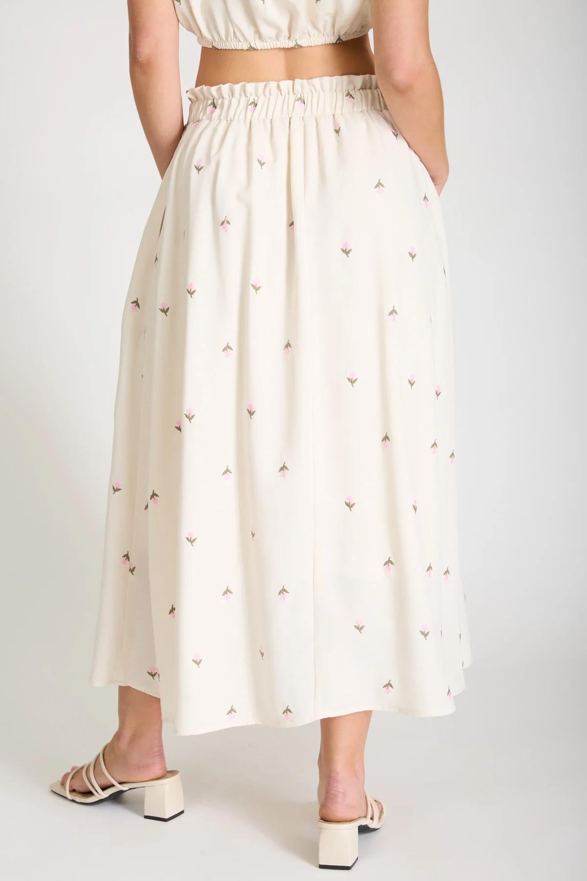 Person wearing a white skirt with small patterns on a plain background