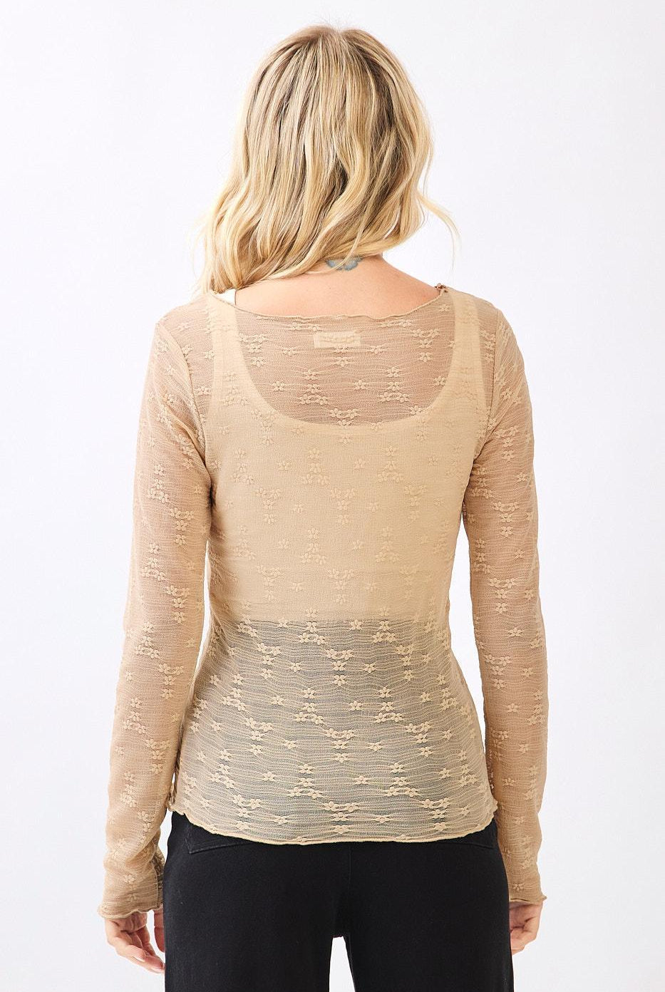 Woman wearing a beige long-sleeve top with a subtle pattern on a white background