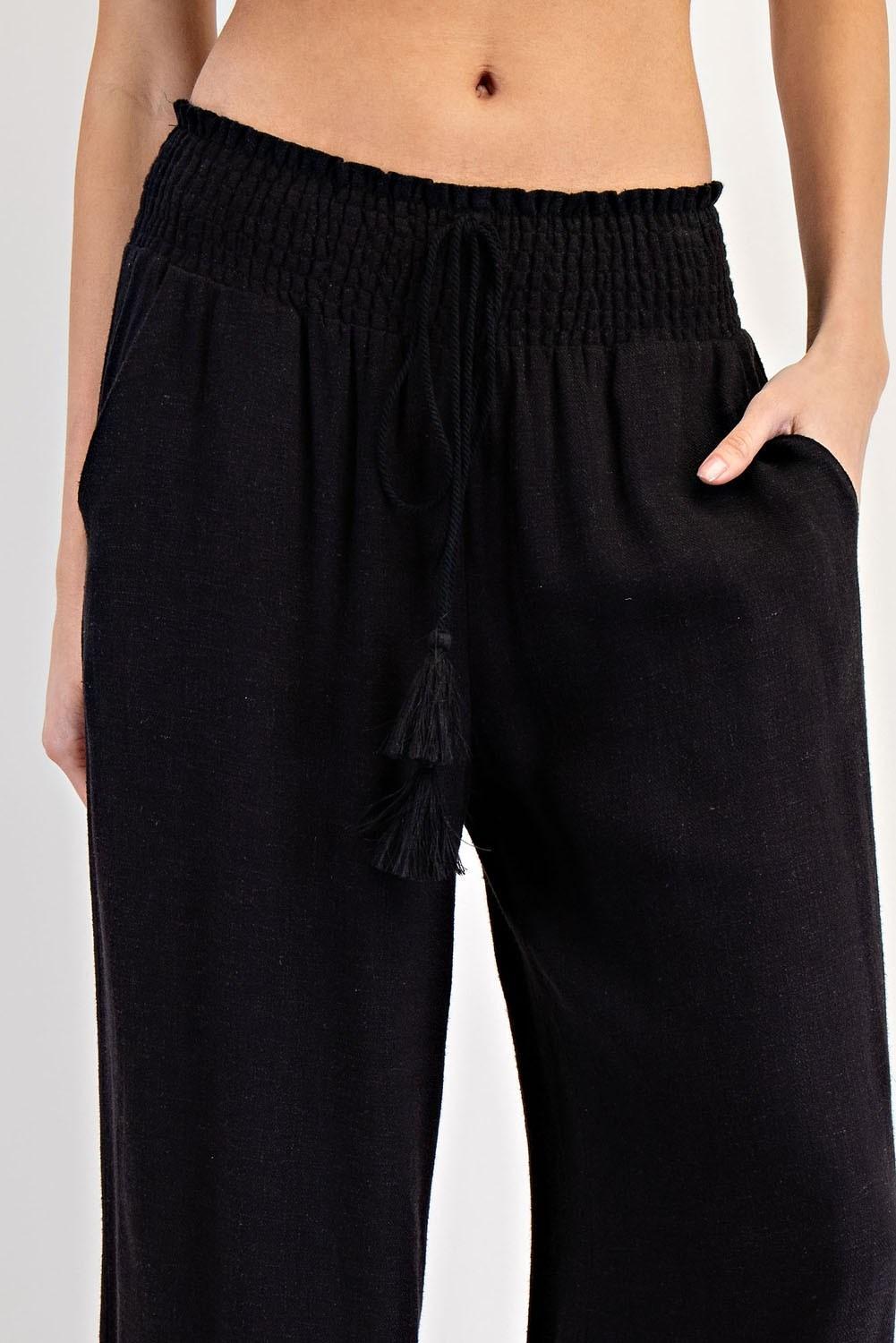 Black pants with tassels worn by a person on a light gray background