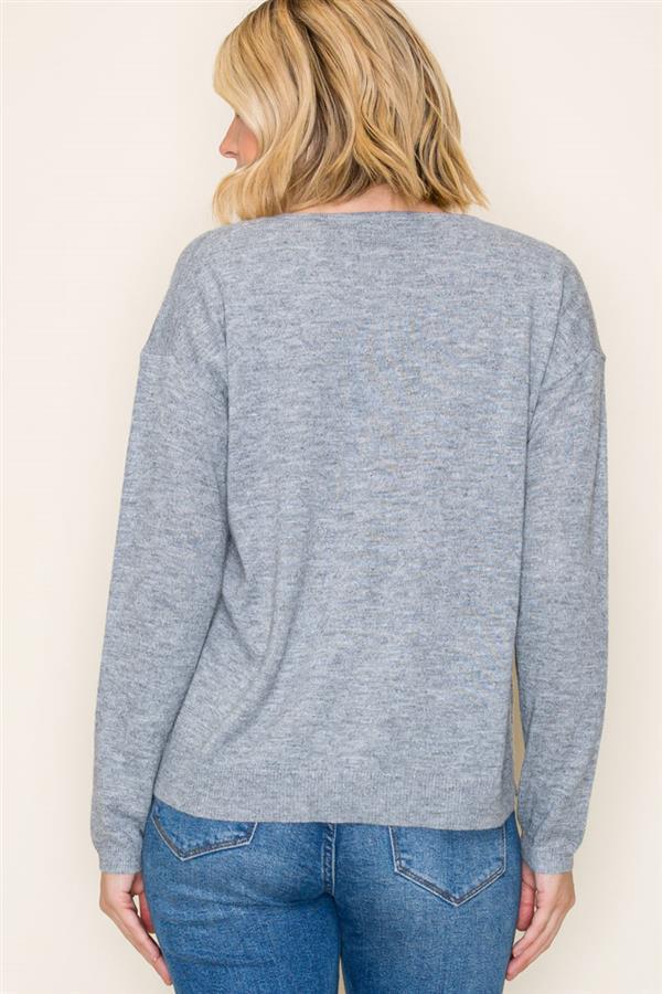 Person wearing a gray long-sleeve top and blue jeans against a beige background