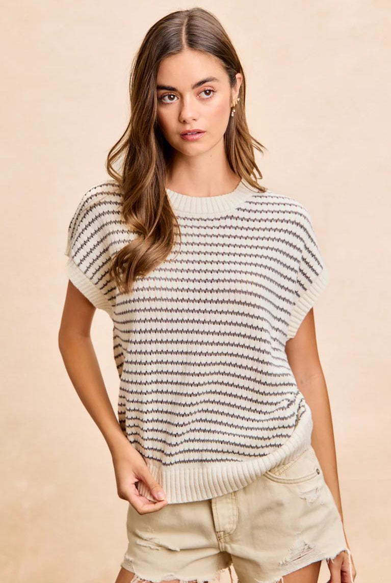 Woman wearing a striped sweater and shorts against a beige background