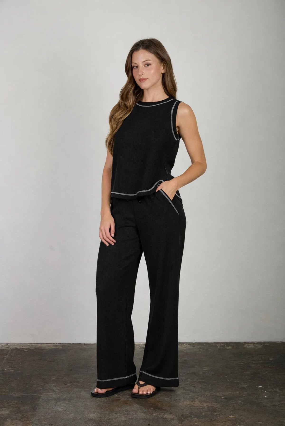 Woman wearing a black outfit with white trim against a plain background