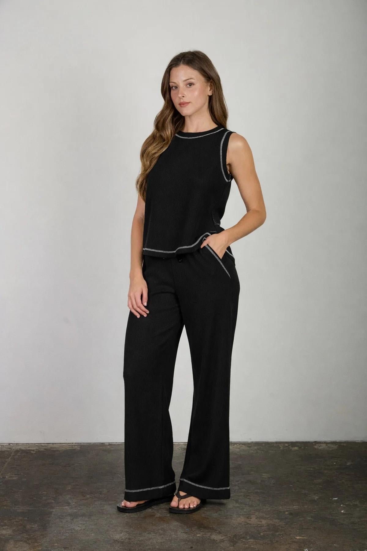 Woman wearing a black outfit with white trim against a plain background