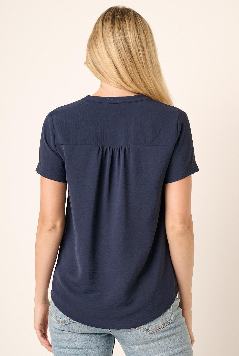 Person wearing a navy blue t-shirt with a plain background