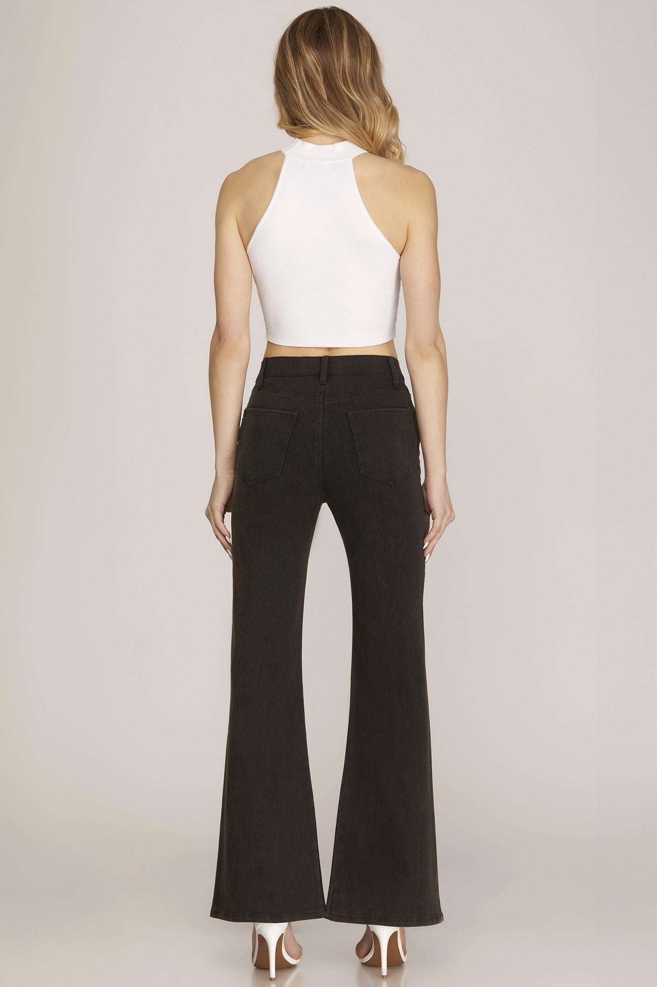 Person wearing a white halter top and black flared pants on a plain background