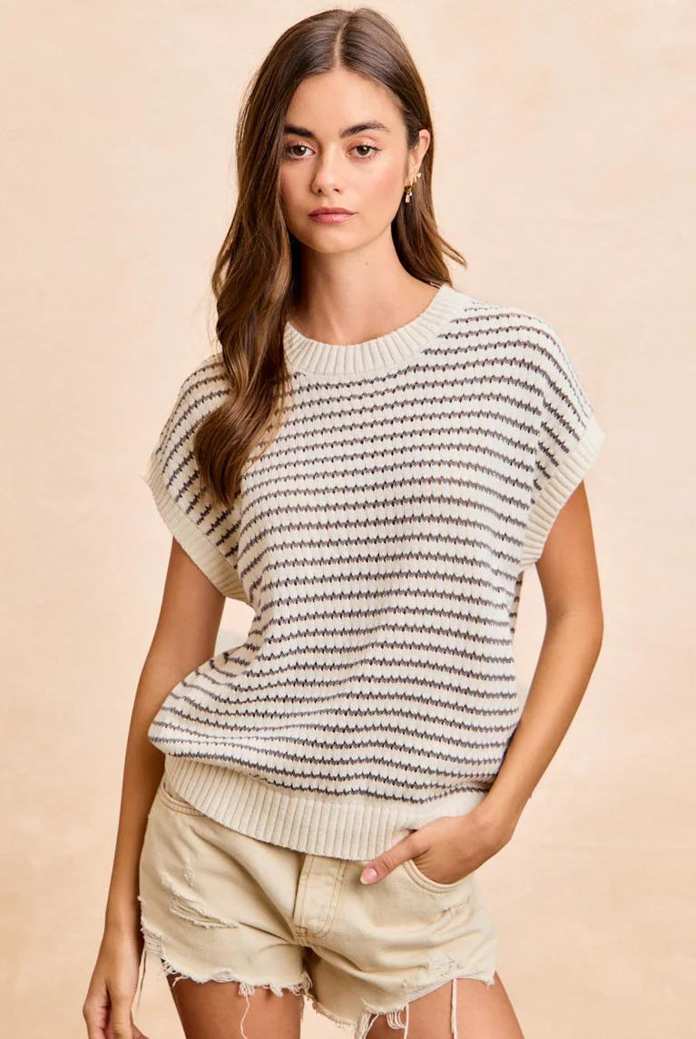 Woman wearing a striped sweater and shorts on a beige background