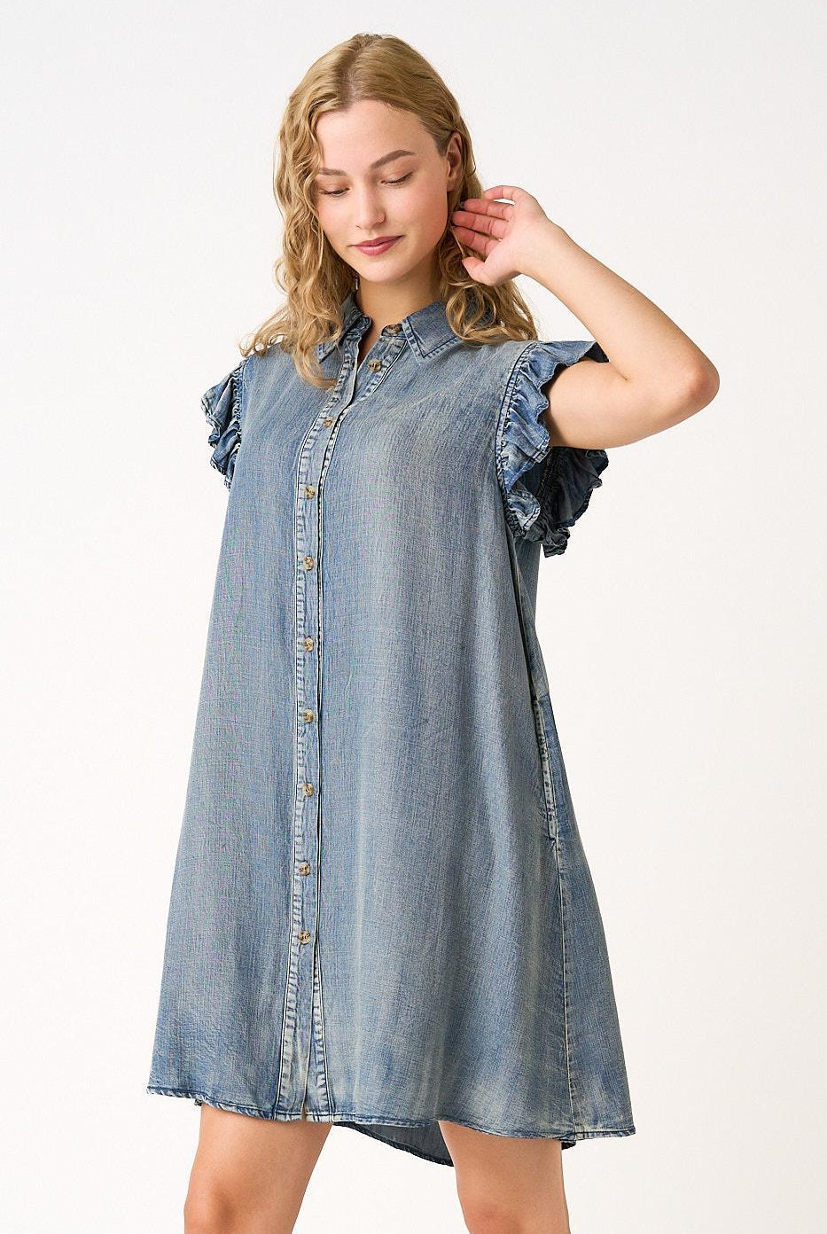 Woman wearing a denim dress with ruffled sleeves on a white background