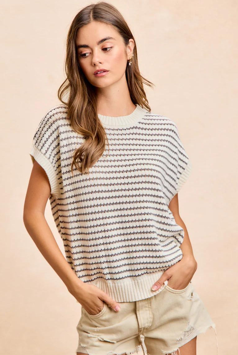 Woman wearing a striped short-sleeve top and shorts on a beige background