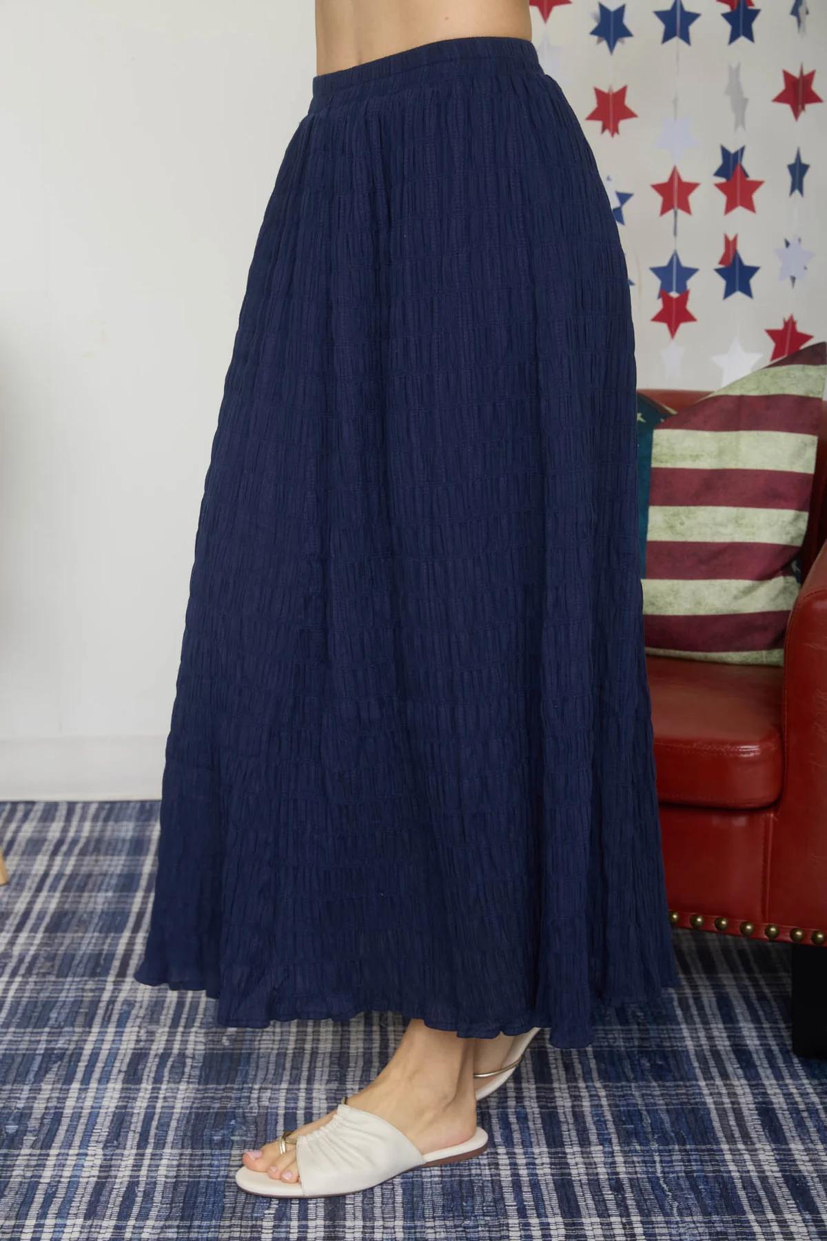 Person wearing a navy blue skirt with a colorful star-patterned curtain in the background.