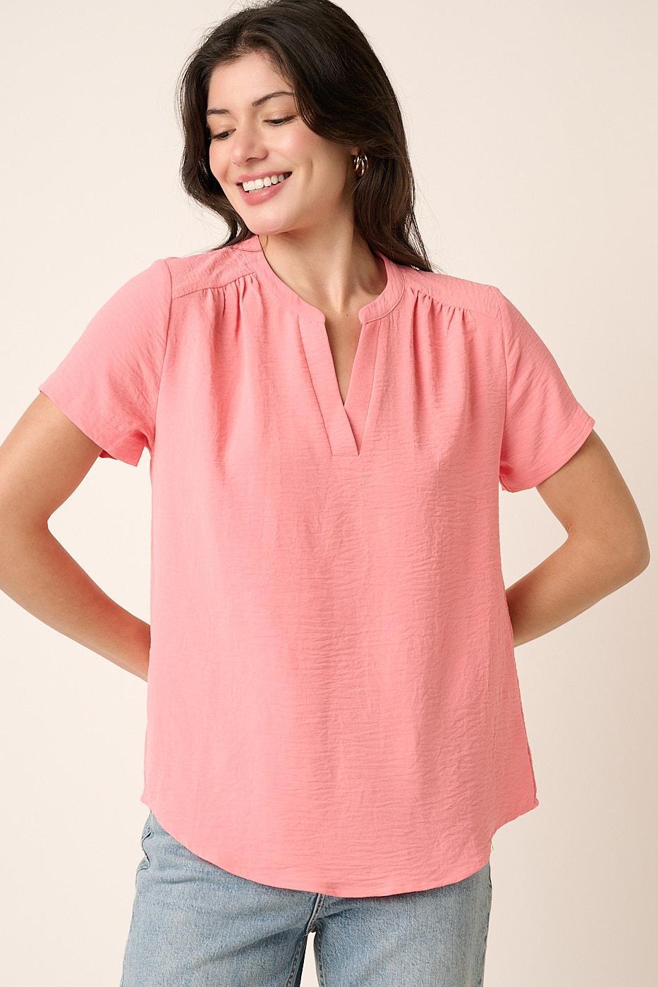 Woman wearing a pink blouse with short sleeves on a beige background