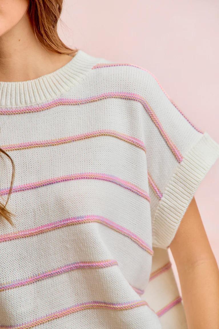Light blue sweater with pink and purple stripes on a pink background