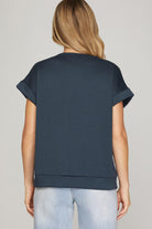 Person wearing a navy blue top and light blue jeans on a gray background