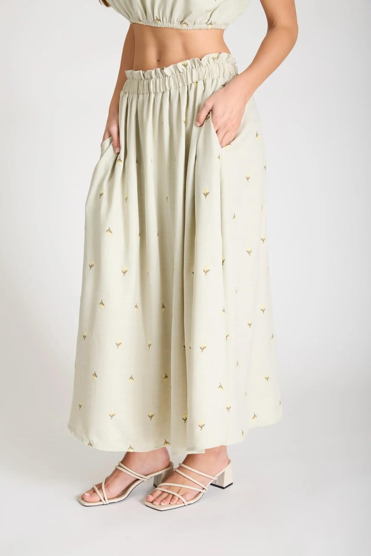 Woman wearing a light green skirt with a subtle pattern on a white background