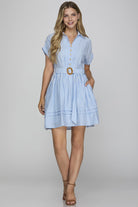 Woman wearing a blue and white striped dress with a belt on a gray background