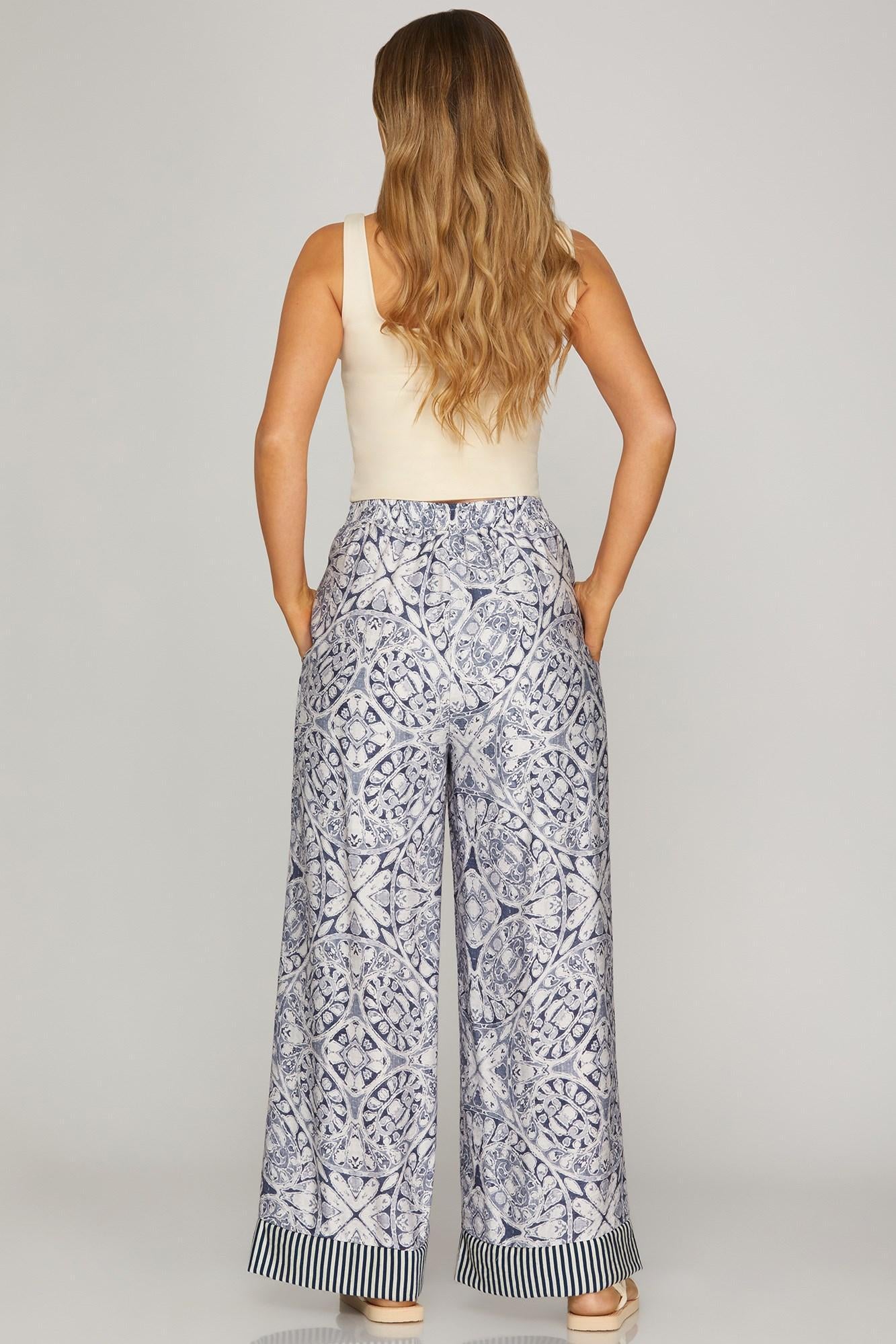 Woman wearing a sleeveless top and patterned pants on a plain background