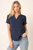 Woman wearing a navy blue top and light blue jeans on a beige background