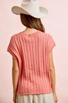 Person wearing a pink knitted top and white hat on a pink background