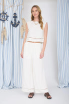 Woman wearing a white outfit standing in front of decorative curtains with anchors.