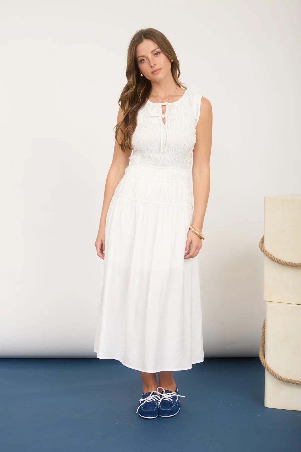 Woman wearing a white dress standing on a blue surface with a white background