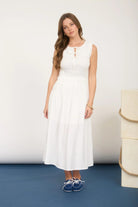 Woman wearing a white dress standing on a blue surface with a white background