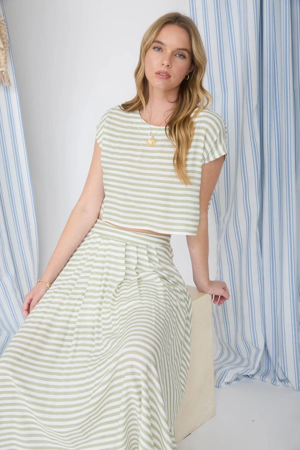 Woman wearing a striped outfit with a blue and white striped curtain in the background