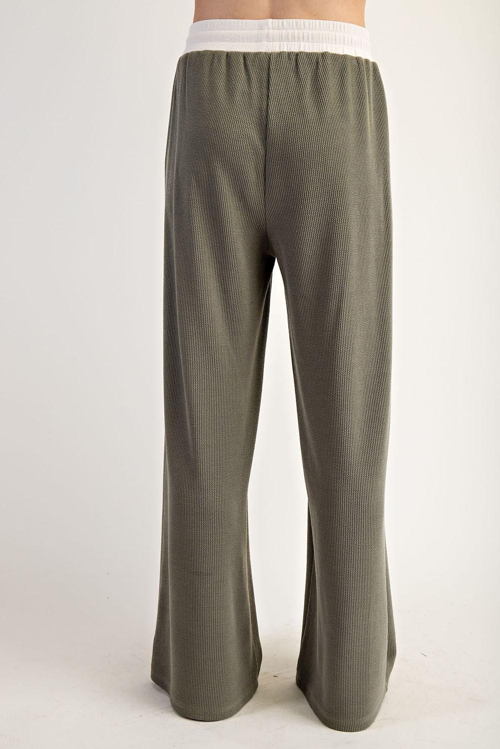 Woman wearing a green outfit with a green and white top on a plain background