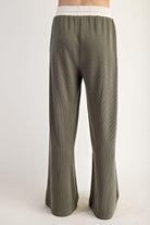 Woman wearing a green outfit with a green and white top on a plain background