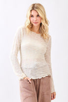 Woman wearing a white lace top and beige pants on a white background