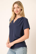 Woman wearing a navy blue top and light blue jeans on a beige background