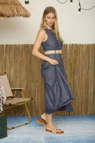 Woman in a blue dress standing in a room with a bamboo wall and blue floor.