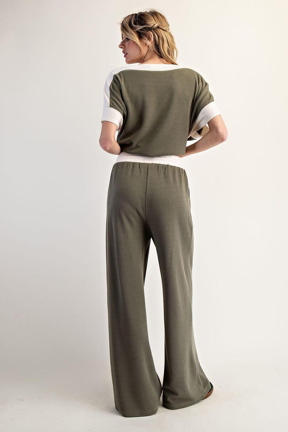 Woman wearing a green outfit with a green and white top on a plain background