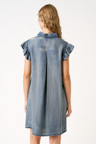 Woman wearing a denim dress with ruffled sleeves on a white background