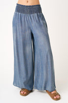 Blue denim wide-leg pants worn by a person on a white background