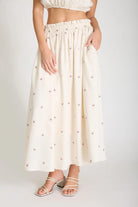 Woman wearing a white skirt with a subtle pattern on a plain background