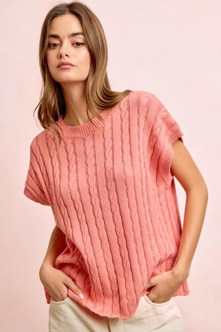 Woman wearing a pink ribbed sweater against a pink background