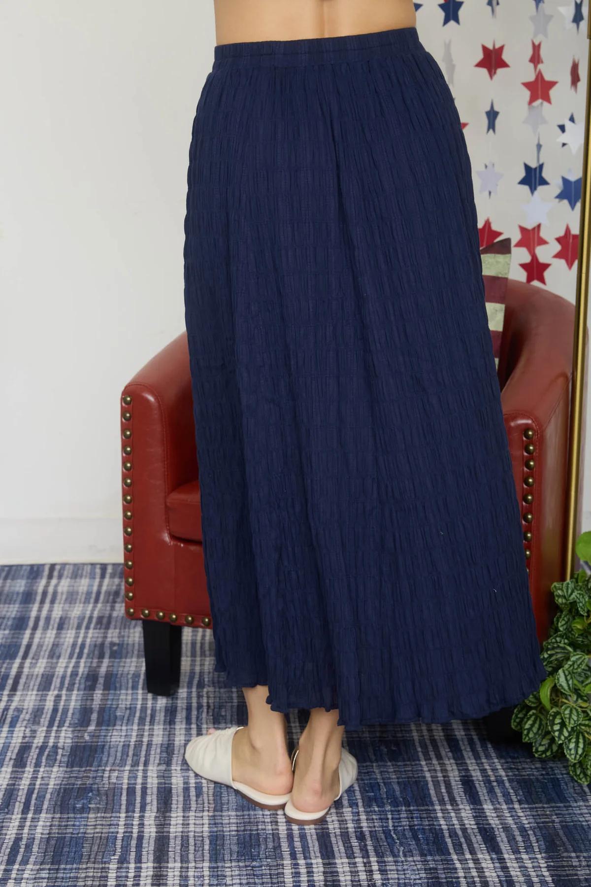 Person wearing a navy blue skirt standing in front of a red chair with star-patterned wallpaper.