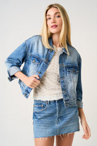 Woman wearing a denim jacket and skirt on a plain background
