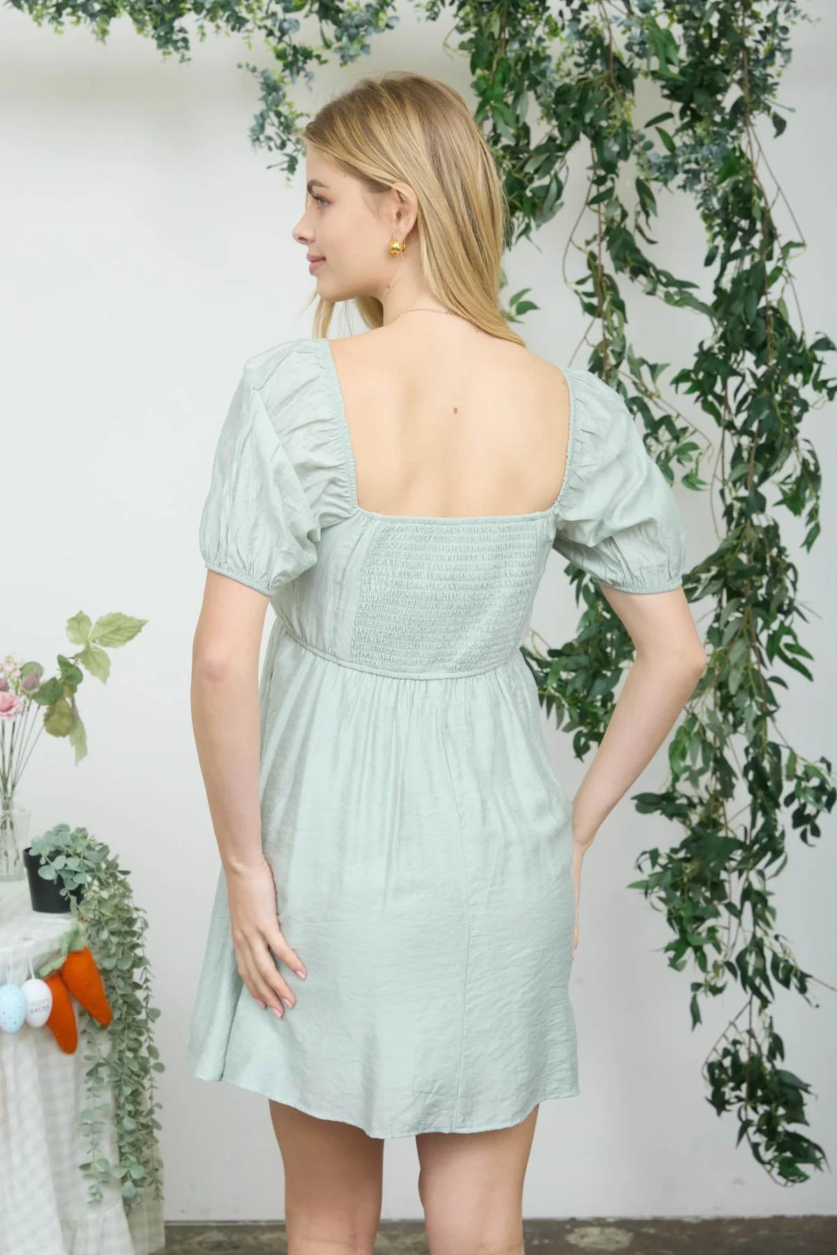 Woman wearing a light green dress with floral decorations in the background