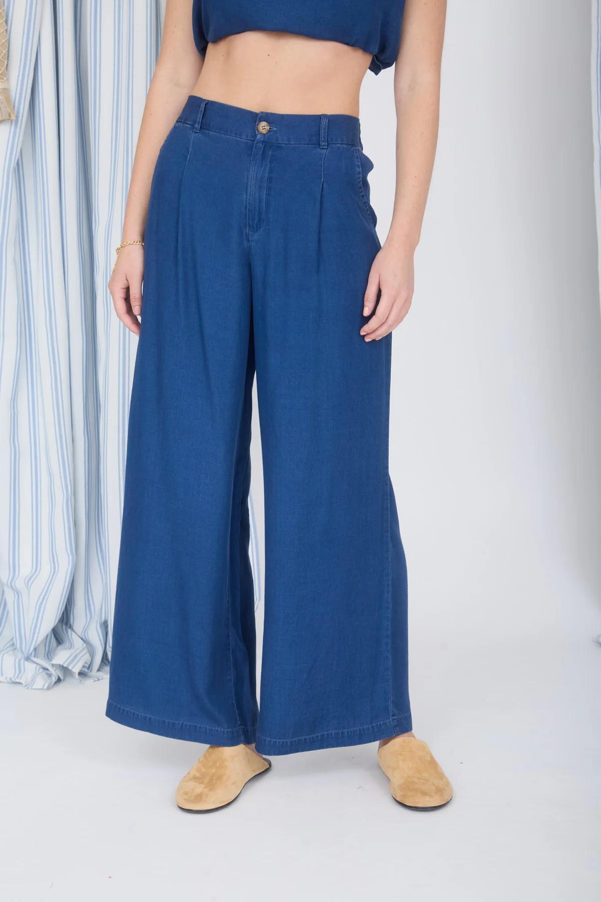 Person wearing blue wide-leg jeans and tan shoes on a white background