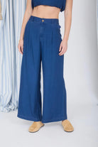 Person wearing blue wide-leg jeans and tan shoes on a white background